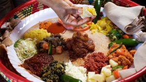 Addis ababa Ethiopia food tour-mahberawi- enjera bread topped with pea,grind meat,chicken stew with eggs,vegitables eating with hand